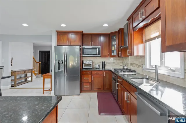 a kitchen with stainless steel appliances granite countertop a refrigerator a sink a stove top oven and a refrigerator