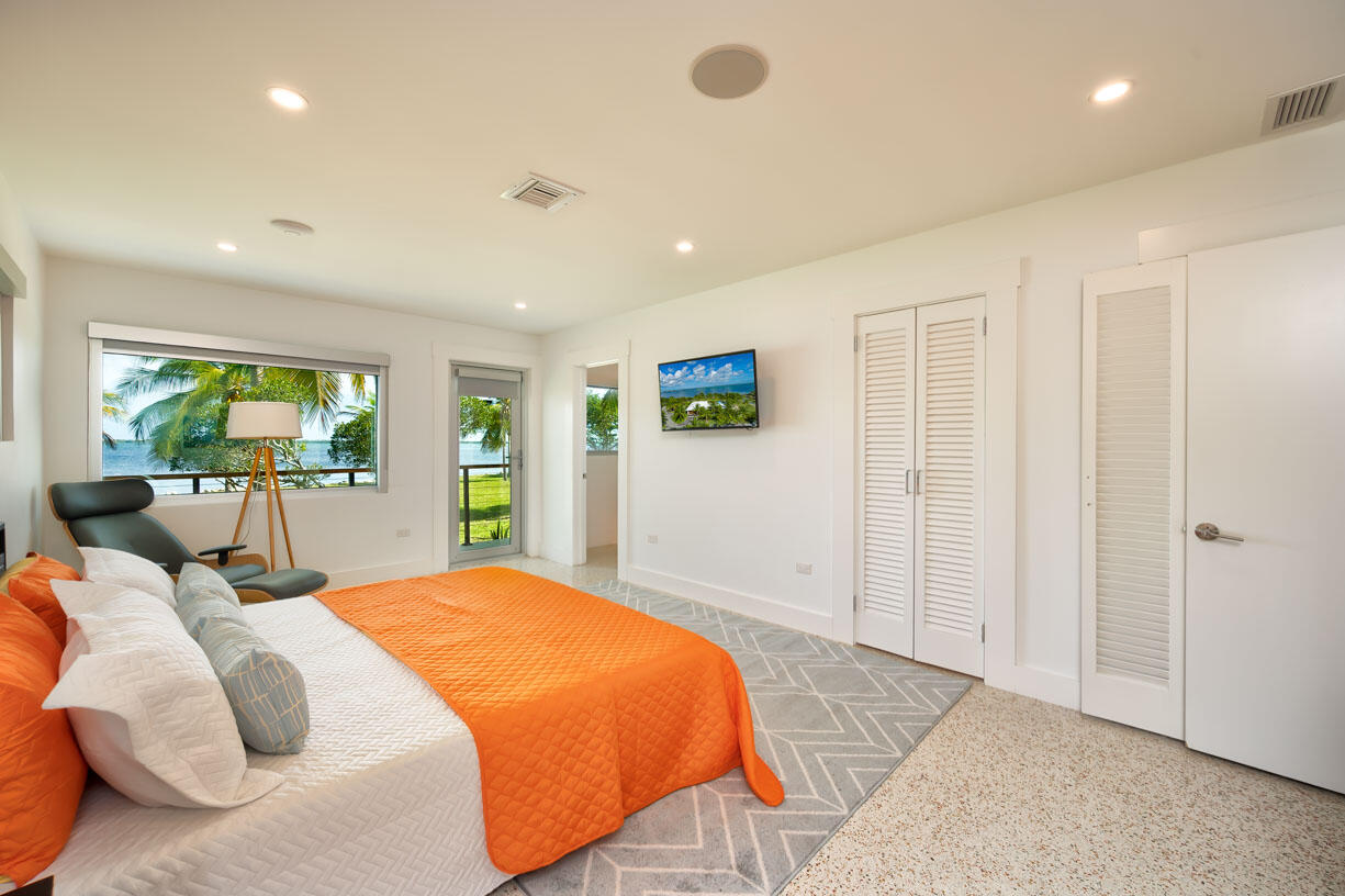 30680 Winifred Street Big Pine Key, FL 33043 - Photo 20 of 73 a spacious bedroom with a large bed and a chandelier