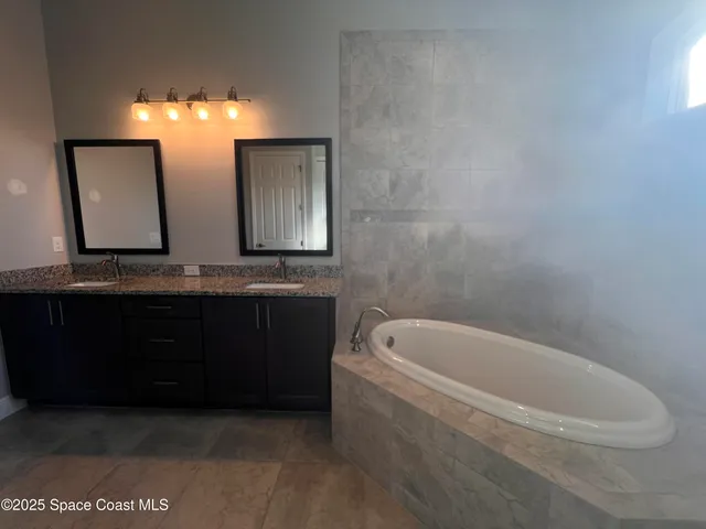 a bathroom with a bathtub a mirror a double vanity sink and vanity