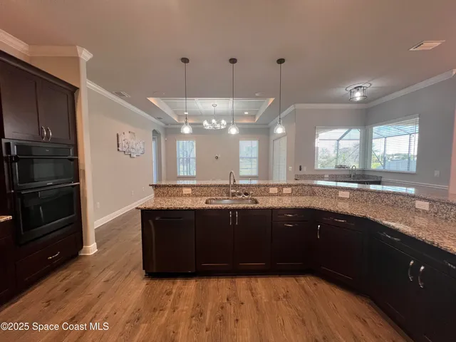 a large kitchen with granite countertop a stove a sink dishwasher a refrigerator and wooden floor