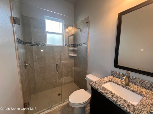 a bathroom with a granite countertop sink toilet and shower