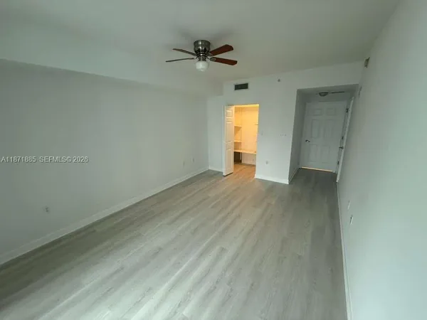 a view of a room with a ceiling fan and wooden floor