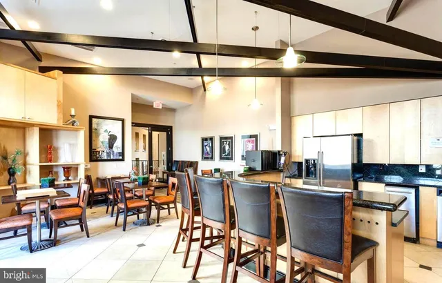 a dining hall with stainless steel appliances granite countertop a table chairs and a wooden floor