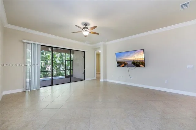 a view of an empty room with a window and chandelier fan