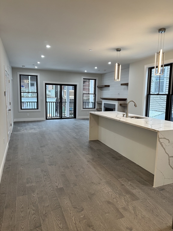 197 Condor Street, Unit 4 Boston, MA 02128 - Photo 2 of 14 a large white kitchen with kitchen island a sink wooden floor and glass doors