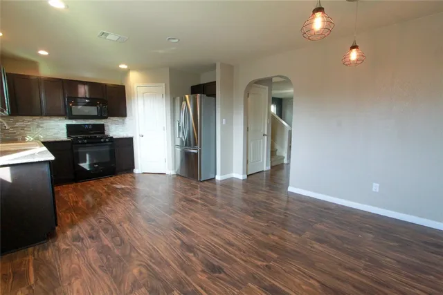 a view of kitchen with stainless steel appliances granite countertop a refrigerator and a stove top oven