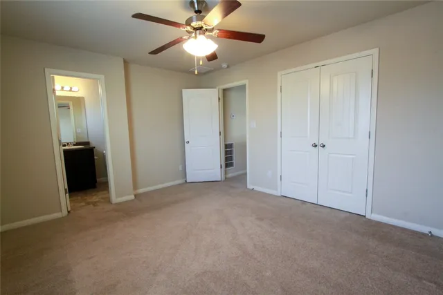 an empty room with closet and a ceiling fan
