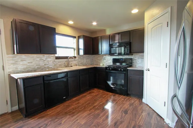 a kitchen with granite countertop a refrigerator and a sink