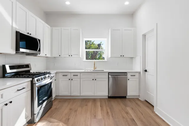 a kitchen with stainless steel appliances granite countertop a stove a sink and a microwave
