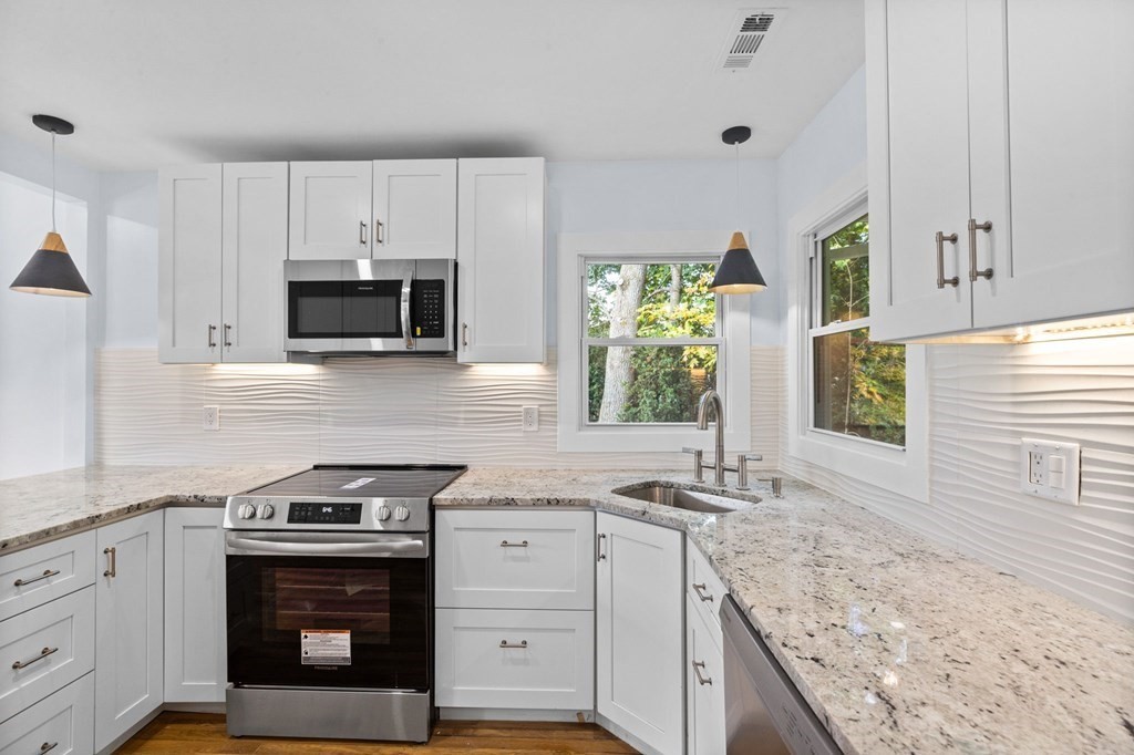 256 Great Road Maynard, MA 01754 - Photo 8 of 26 a kitchen with granite countertop a stove a sink and a microwave