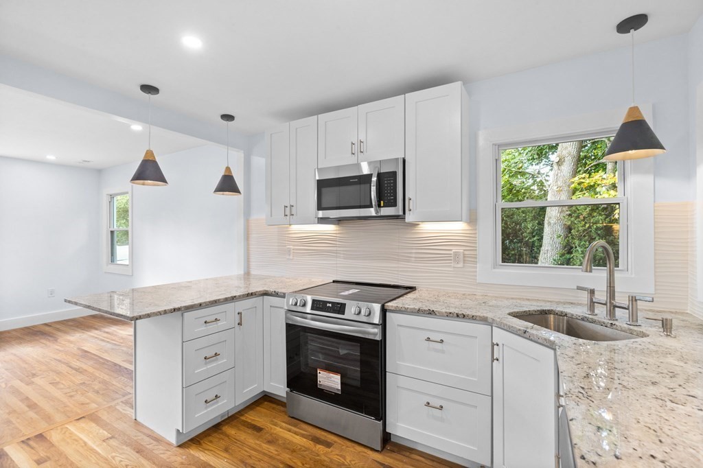 256 Great Road Maynard, MA 01754 - Photo 9 of 26 a kitchen with granite countertop a stove a sink and a microwave