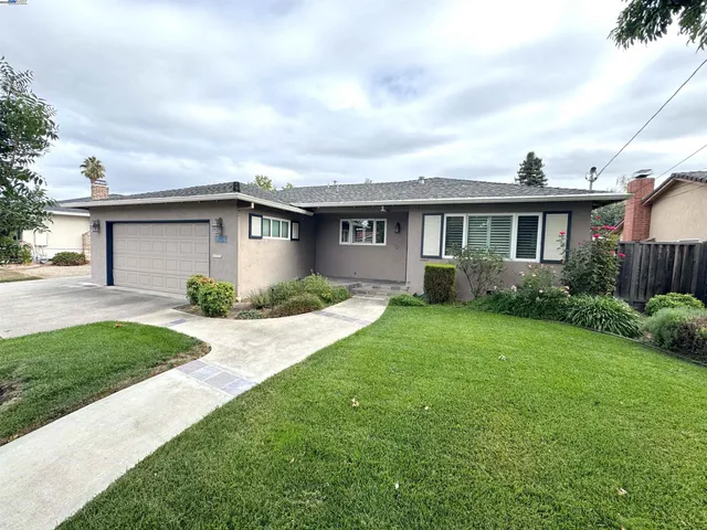a front view of a house with a yard and potted plants
