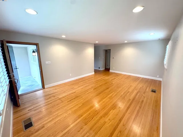 a view of an empty room with wooden floor and a window