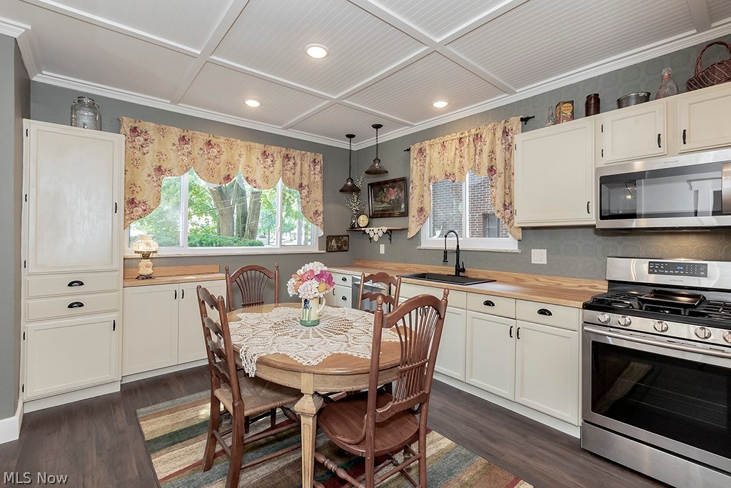 3090 Warren Road Cleveland, OH 44111 - Photo 8 of 50 Kitchen featuring dark hardwood / wood-style flooring, coffered ceiling, pendant lighting, and stainless steel appliances