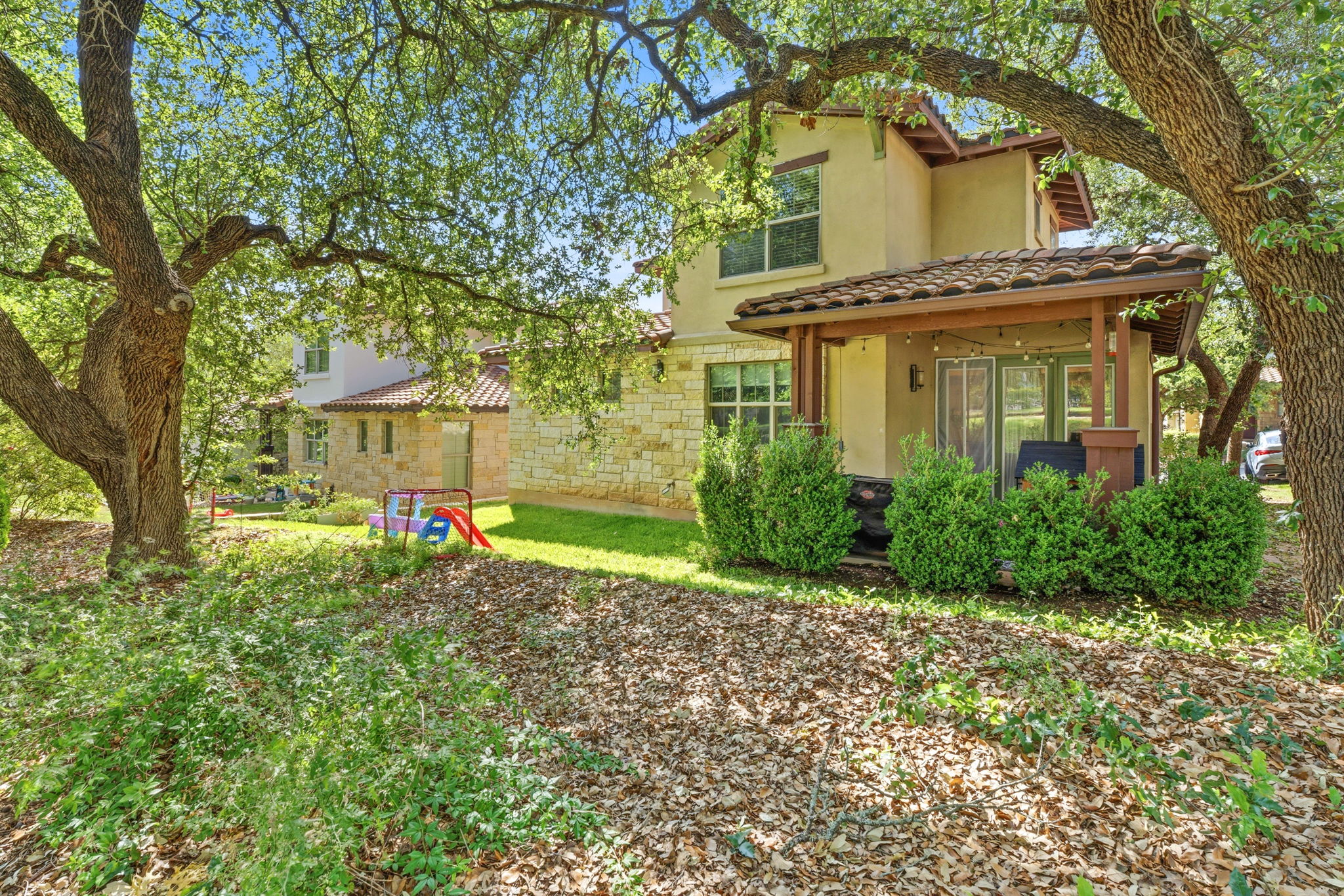 15317 Falconhead Grove Loop Austin, TX 78738 - Photo 27 of 36 Exterior featuring a covered patio with string lighting, stucco siding, and stone accents