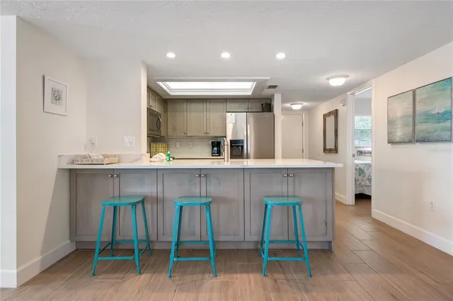 a kitchen with kitchen island granite countertop wooden floors and a view of living room