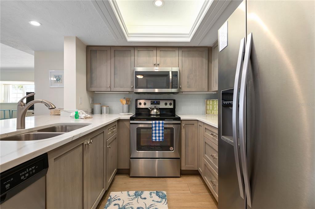 5963 Midnight Pass Road, Unit 332 Sarasota, FL 34242 - Photo 14 of 49 a kitchen with stainless steel appliances granite countertop a sink a stove a refrigerator and a microwave