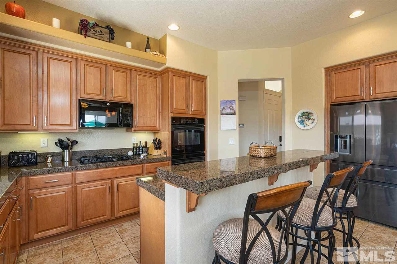 1170 South University Reno, NV 89512 - Photo 13 of 14 a kitchen with stainless steel appliances granite countertop a stove top oven a sink a dining table and chairs