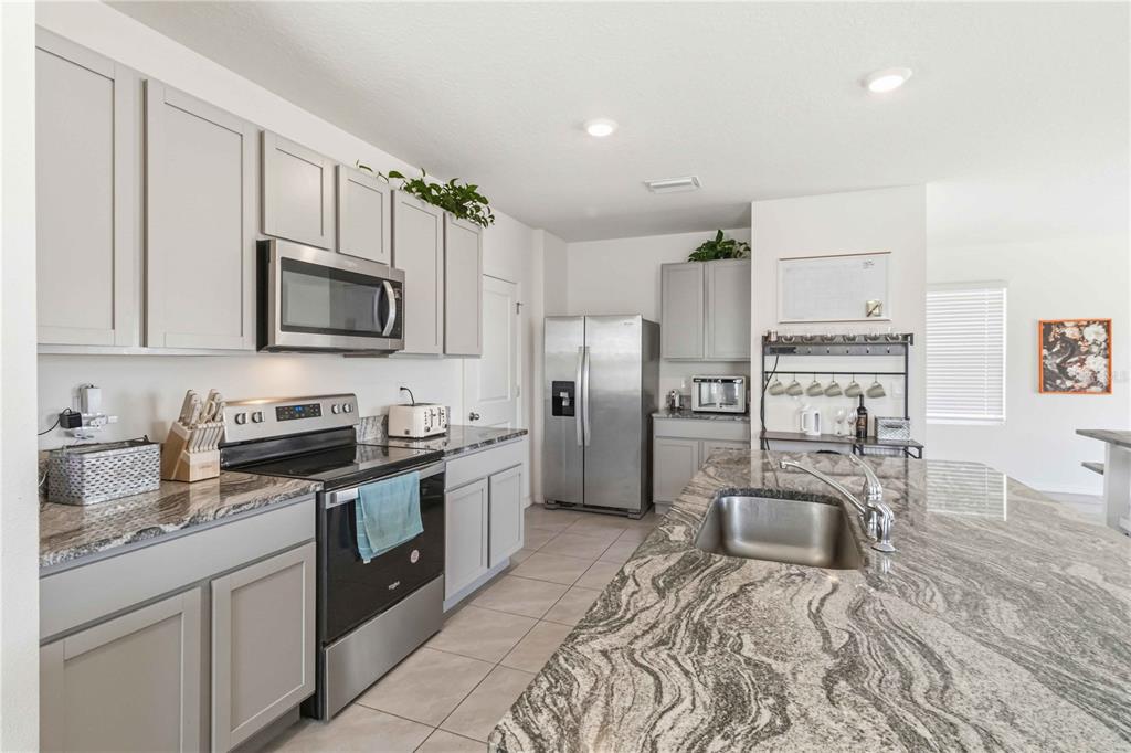 8354 Hardy Bay Loop Wesley Chapel, FL 33545 - Photo 5 of 32 a kitchen with stainless steel appliances granite countertop a stove top oven a sink dishwasher a refrigerator and cabinets with wooden floor