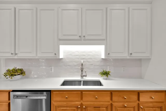 a kitchen with stainless steel appliances granite countertop white cabinets and a window