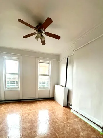 a view of empty room with wooden floor and fan