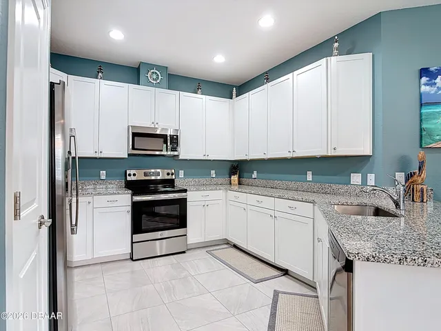 a kitchen with granite countertop white cabinets and stainless steel appliances