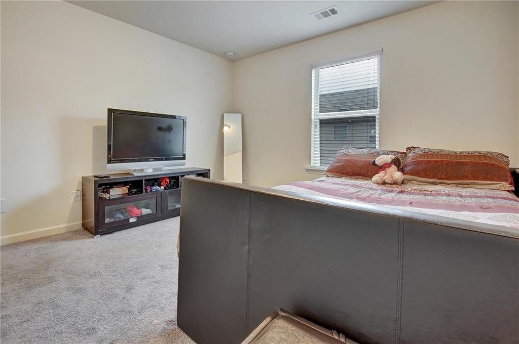 7687 Cabrini Place Fairburn, GA 30213 - Photo 27 of 29 a bedroom with a bed and a flat screen tv