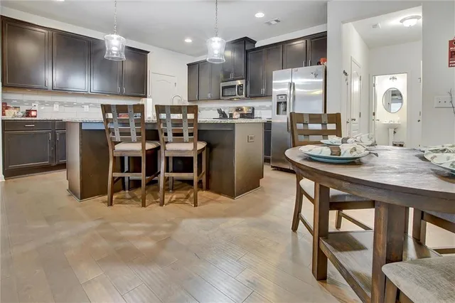 a kitchen with kitchen island a dining table and chairs