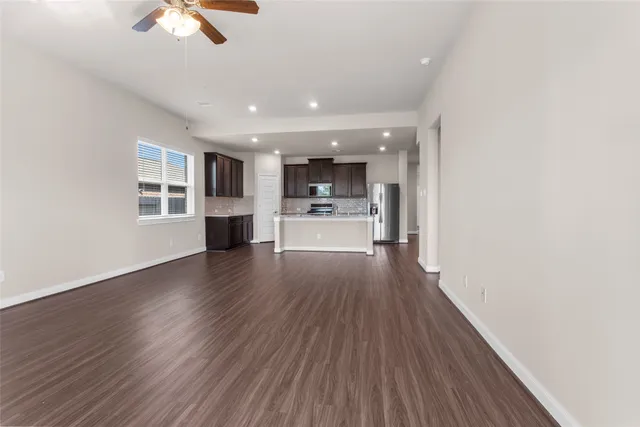 a view of a big room with wooden floor a ceiling fan and windows