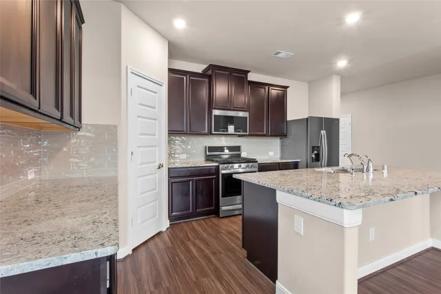 a kitchen with stainless steel appliances granite countertop a sink stove and refrigerator