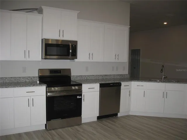 a kitchen with white cabinets and black appliances