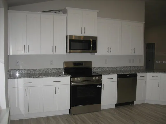 a kitchen with white cabinets and black appliances