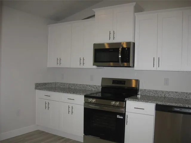 a kitchen with white cabinets and black appliances