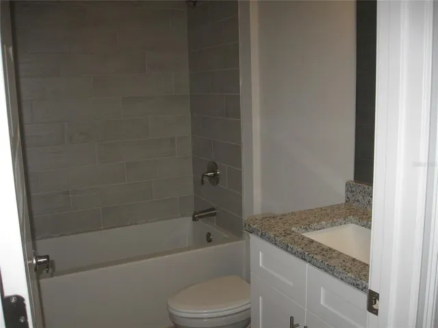 a bathroom with a granite countertop bathtub shower and toilet
