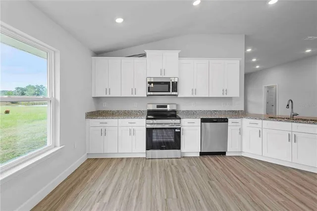 a kitchen with stainless steel appliances granite countertop a stove a sink and white cabinets