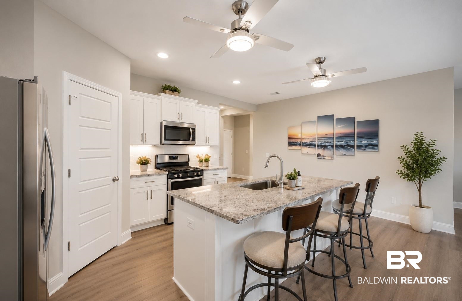 31468 Memphis Loop Daphne, AL 36527 - Photo 4 of 24 Open-concept kitchen featuring an island with a built-in sink, stainless steel appliances, white cabinetry, and wood-finish flooring