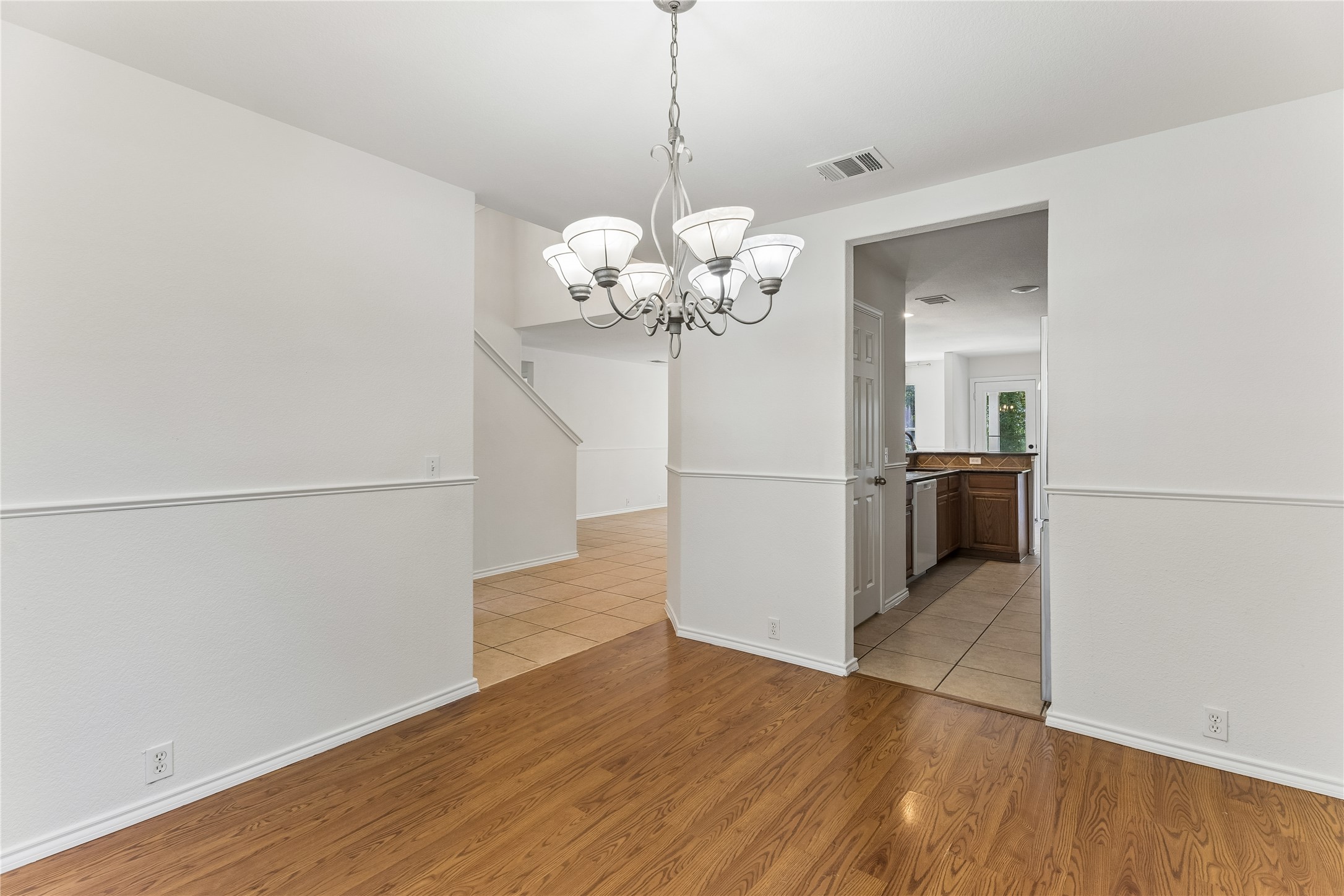 2372 Paradise Ridge Drive Round Rock, TX 78665 - Photo 5 of 40 A graceful chandelier illuminates the rich wood flooring of this dining space, flowing seamlessly into the tiled kitchen.