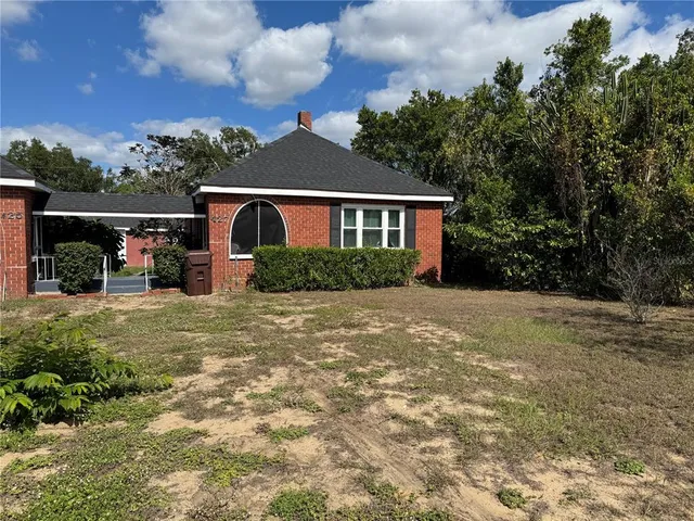 a front view of house with yard and trees in the background