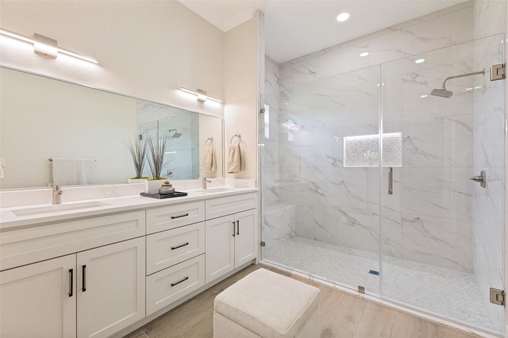 3150 Crisp Road Ennis, TX 75119 - Photo 16 of 30 Spacious primary bathroom featuring a dual vanity with white cabinetry and quartz countertops, an expansive mirror, and a glass-enclosed shower with large format marble-look tile walls and a hexagonal tile floor