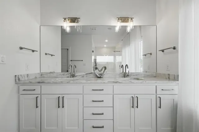 a bathroom with a granite countertop sink a mirror and shower