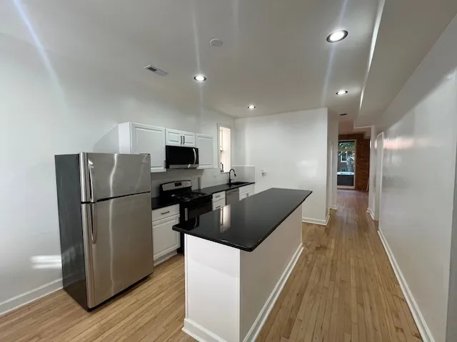 a kitchen with stainless steel appliances granite countertop a refrigerator a sink a stove and cabinets