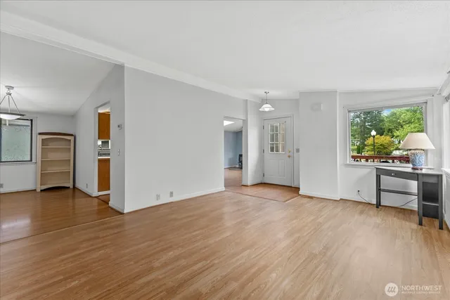 a view of an empty room with window and wooden floor