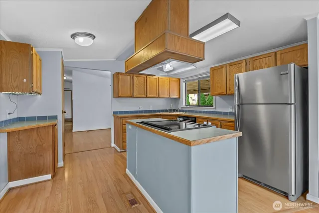 a kitchen with stainless steel appliances granite countertop a refrigerator a stove and a wooden floors
