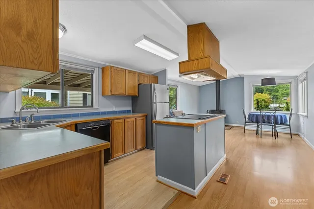 a kitchen with stainless steel appliances granite countertop wooden cabinets a stove a sink a window and chairs