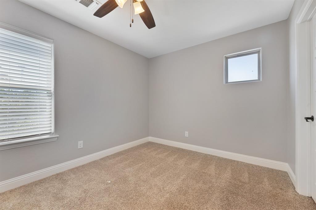 1713 Bronco Road Granbury, TX 76049 - Photo 21 of 23 Carpeted room with a ceiling fan light fixture, two windows, and white baseboards