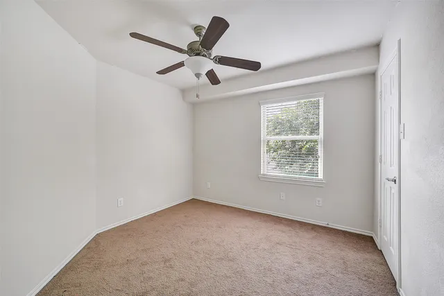 an empty room with a window and a fan