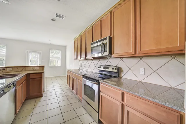 a kitchen with stainless steel appliances granite countertop a stove a sink and a microwave
