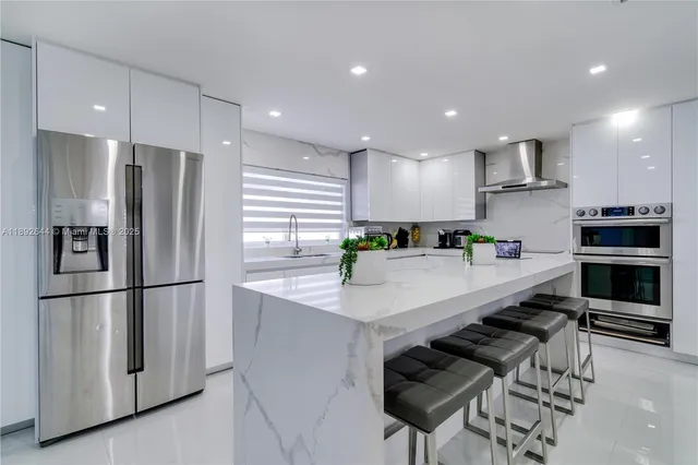 a kitchen with stainless steel appliances granite countertop a refrigerator a sink and a stove