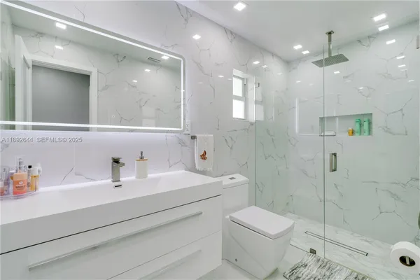 a bathroom with a sink a toilet a mirror and shower
