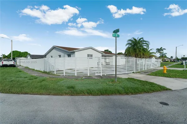 a view of a white house with a yard and entertaining space